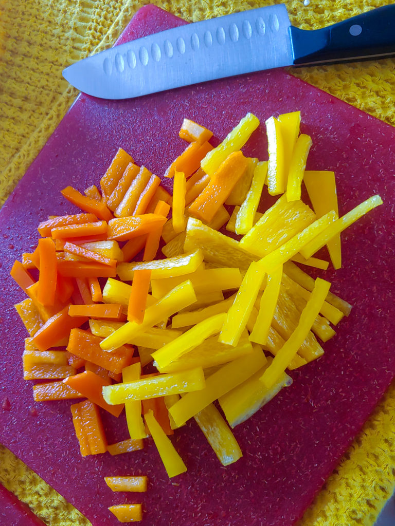 sliced yellow and orange bell peppers on a red cutting board